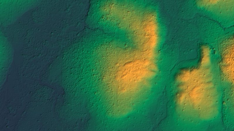 O terreno da mesma área sem a vegetação, colorido do azul ao verde e ao amarelo conforme a altitude, com a escala de altitude embaixo